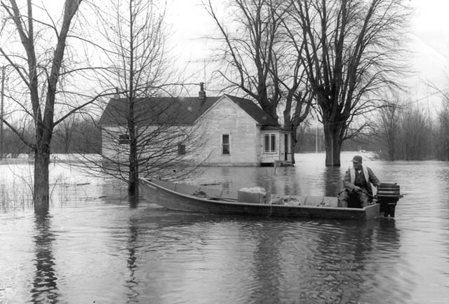 <B>Flooded out resident</B> using his skiff and Mercury outboard to negotiate the flood waters near Beardstown, Illinois (undated)