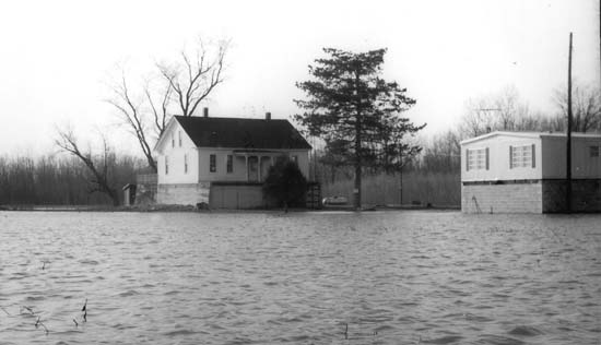<B>High Water</B> encroaching upon a house and mobile home in this undated photograph. The homes have been built on eight-foot-tall foundations as a precaution against repeated flooding.