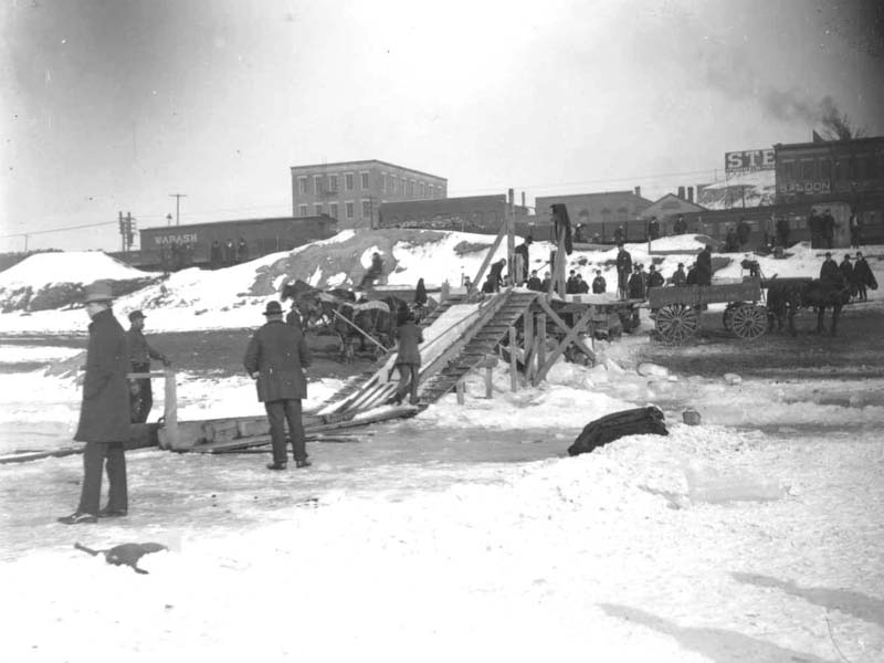 <B>Ice Conveyor</B><BR>This 1900 photograph shows the blocks of ice being pushed up the ice conveyor to a higher level of the riverbank. The men will load it onto the wagon, which will take it to the ice house for storage.