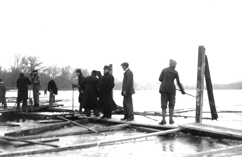 <b>Cutting Ice Up Bay - High School Boys 2</B><BR>The boys are standing on a platform at the edge of the ice. They will clear the snow from the next section before continuing to cut.