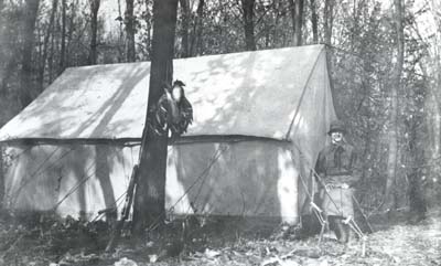 <b> Grace and I Camp in the Ash Flat </b>, circa 1903-1920.  Ducks and the  rifle used to hunt them are leaning on a tree.