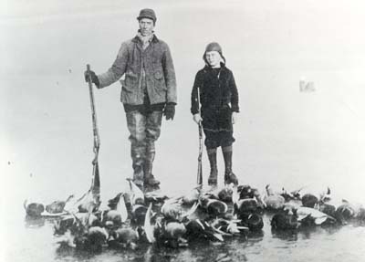 <b>Duck Hunters on Ice</b>.  A man and his son with their days kill spread across the ice.