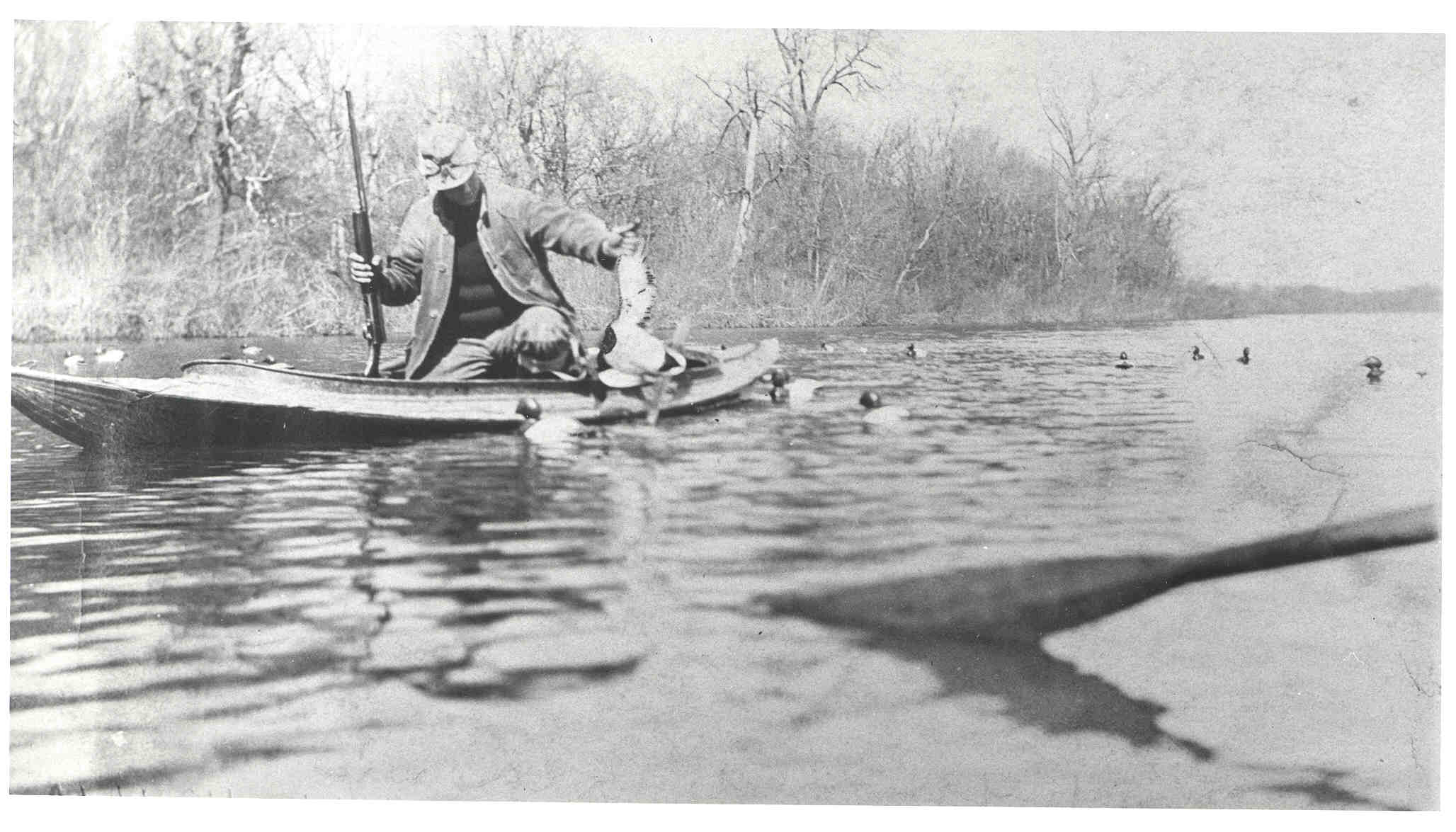 <b>Page Hatch - Shelly Lake</b>, circa 1903-1920.<br>Page is retrieving a duck from among the decoys, in a Mullins steel duck boat.