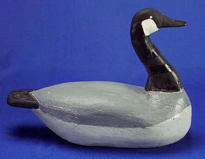 <b>Canada Goose Decoy</b>, no date.<br>  Louis Hahn, Havana, Illinois. <br>Wood, 20 inches long.<br>Illinois State Museum Collection (1967.19, 798963)  <br>Gift of Herman Glick, Havana, Illinois.  <p>Hahn was a market hunter who made solid wood decoys of ducks and geese between 1900 and 1920.  They are often crudely formed from telephone pole wood and painted without much detail.  The goose decoy has been repaired with a metal band around the neck and repainted. </p><p>He is known for using a human hunter decoy when hunting geese in marshes.  He positioned this cutout man at the opposite end of the marsh, pulled a wire to raise it to a standing position, thus flushing the geese toward him.