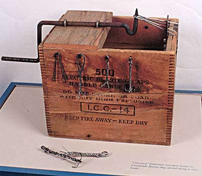<b>Box to make Crowfoot Hooks</b><br>Replica of a box used to make crowfoot hooks. The wires twist when the handle is turned. Note a hook in four stages of construction on the front of the box.<br> Jake Wolf Fish Hatchery exhibit, Topeka, Illinois.