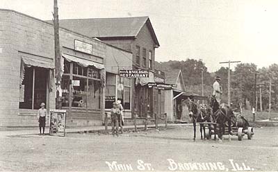 <b>Main Street, Browning</b>, circa early 1900s.  From left to right, a bank, John Trone's store, Arnold's Restaurant, and a grocery store.  Deery-man William Crafton can be seen standing in his horse-drawn wagon.