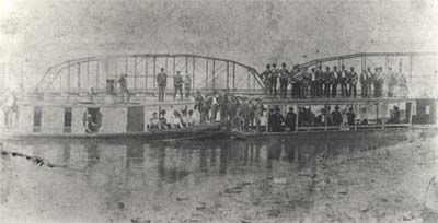 <b>Dedication of the Beardstown Bridge</b>, circa .  The Browning Marine Band stands on top of the barge Myrtle, and other dignitaries stand on the bridge and on the launch, the Edith K.  The launch and barge was owned by Charles H. Waters, owner of the Waters Fish Company.