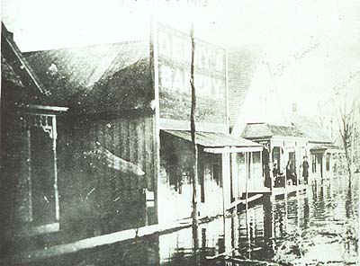 <b>High Water in Browning</b>, 1913.  From right to left, Henry Pettigew home, Derry's Bakery, Oliver Harris home, and Frank Weishaar home.