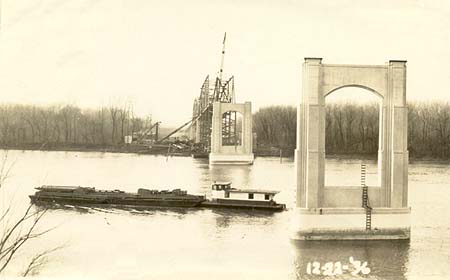 <b>The Bridge Under Construction</b>.  A barge passes under the partially-finished Scott W. Lucas Bridge at Havana, Illinois, circa December 23, 1936.