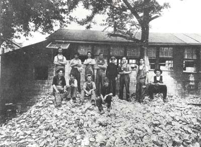 <b>Button Cutters on a Pile of Shells</b> outside a button factory, 1919.