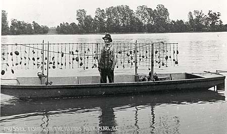 <b>Mussel Harvester, Pearl, Illinois</b><br>Musseler in a johnboat with catch of mussels on crowfoot hooks along the bar.