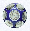 Overlay with Garland MillefioriFranceBaccarat, circa 1845-55Diameter: 8.2 cm (3 1/4 inches)(702258)Double overlay (opaque white overlaid with dark blue), enclosing a garland millefiori design comprised of two interlocked trefoils and isolated millefiori canes; overlay decorated with gilded scrollwork; sides cut with six circular printies, one on top
