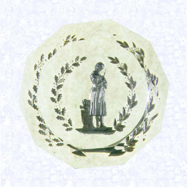 <B>Joan of Arc Sulphide<BR>France<BR>Baccarat, circa 1845-55</B><BR>Diameter: 8.6 cm (3 3/8 inches)<BR>(702336)<BR><BR>Sulphide scene of Joan of Arc, shown standing holding her sword, her helmet resting on a stand behind her; partially encircled by a wreath of oak and laurel leaves; sides cut with triangular facets, ten-sided facet cut on top
