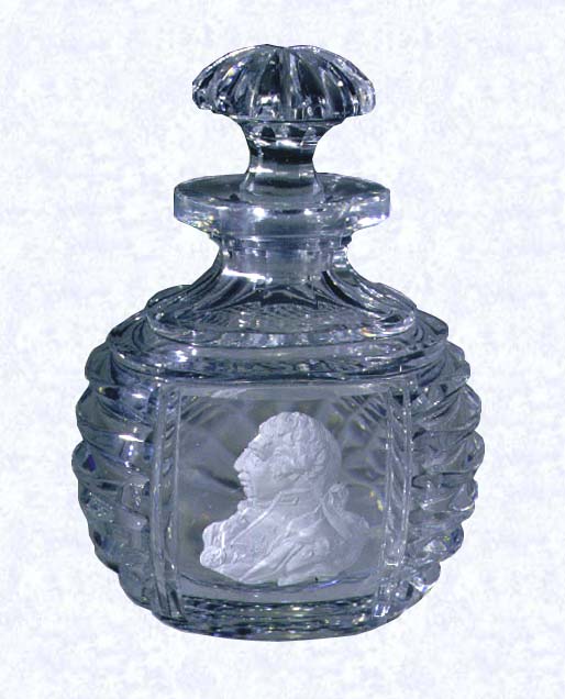 <B>Sulphide Portrait on Bottle<BR>England<BR>Apsley Pellatt (attributed) circa 1819-1840</B><BR>Width: 7.6 cm (3 inches) Height: 10.5 cm (4 1/8 inches)<BR>(702469)<BR><BR>Cut-Glass bottle with stopper; sulphide profile portrait of George III set in panel on obverse side; diagonal cuts on reverse panel; deeply grooved, horizontal cuts on shoulders and side edges; mushroom-shaped stopper cut with deep radial facets